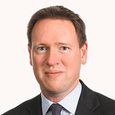 A person wearing a suit and tie smiling at the camera

Description automatically generated